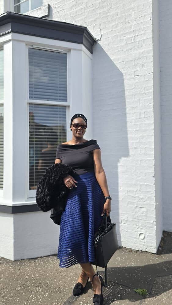 Omowunmi smiling outdoors in an elegant off-shoulder outfit
