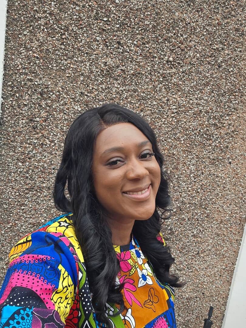 Portrait of Omowunmi Esther Oyeleke smiling, wearing a colourful Ankara print