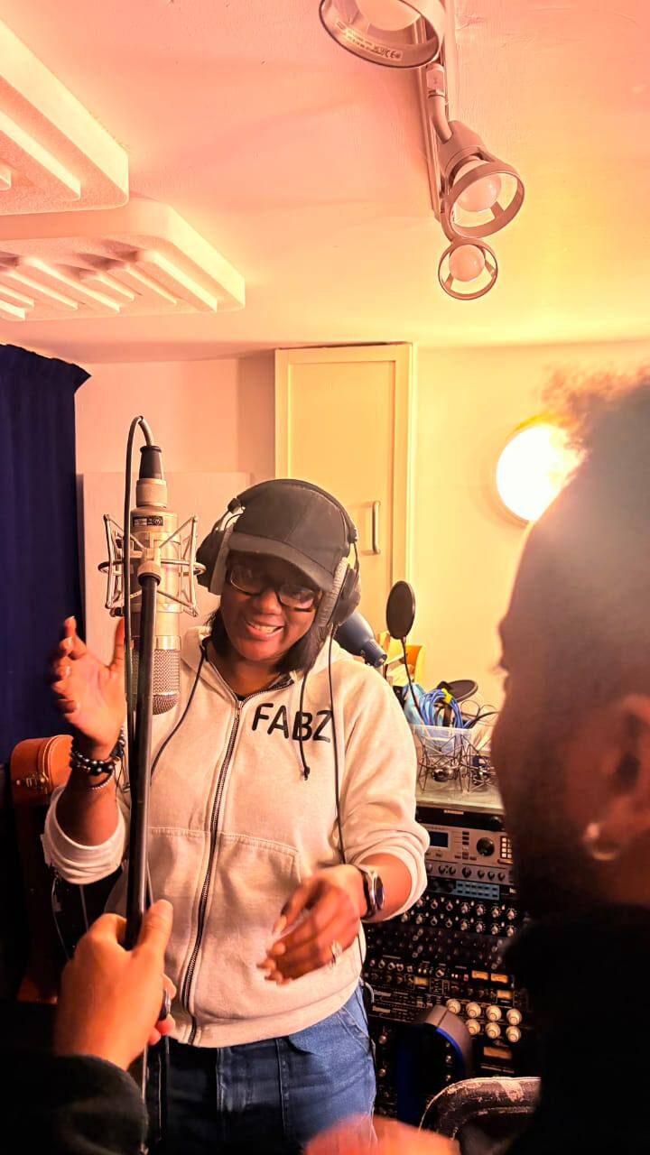 Omowunmi recording vocals at the microphone in the studio